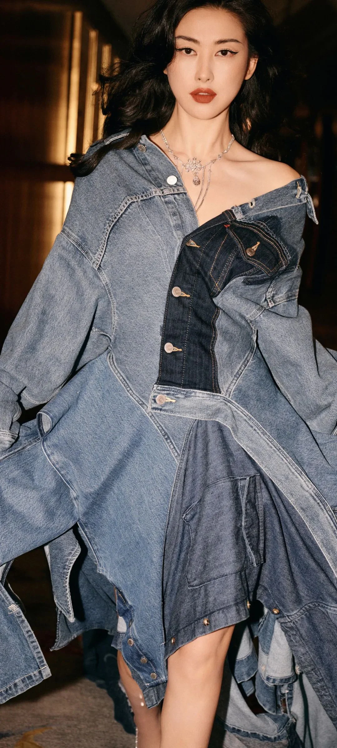 重ね着したデニム服を着た成人女性が屋内に立っています。