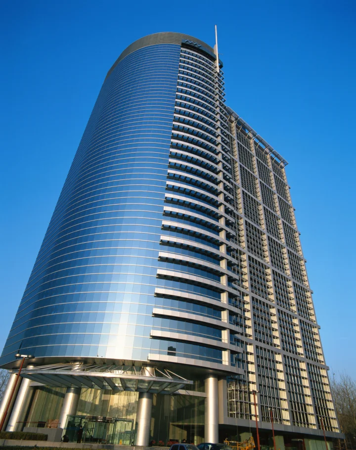 一座现代弧形高层建筑在晴朗蓝天下向上延伸。