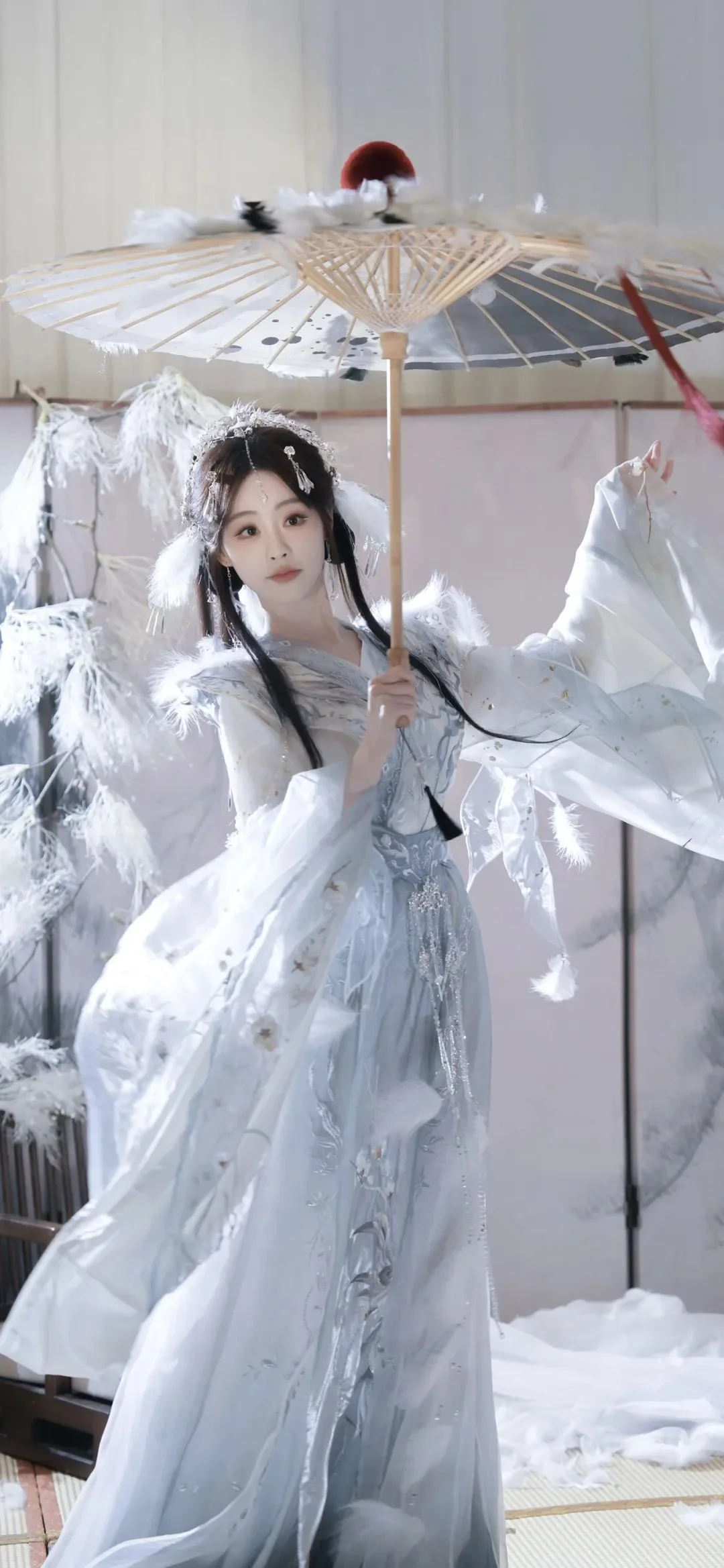 一名身穿白色传统服饰的女性在室内撑着装饰伞。