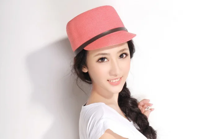 一名戴粉色帽子的女性在浅色背景前微笑。