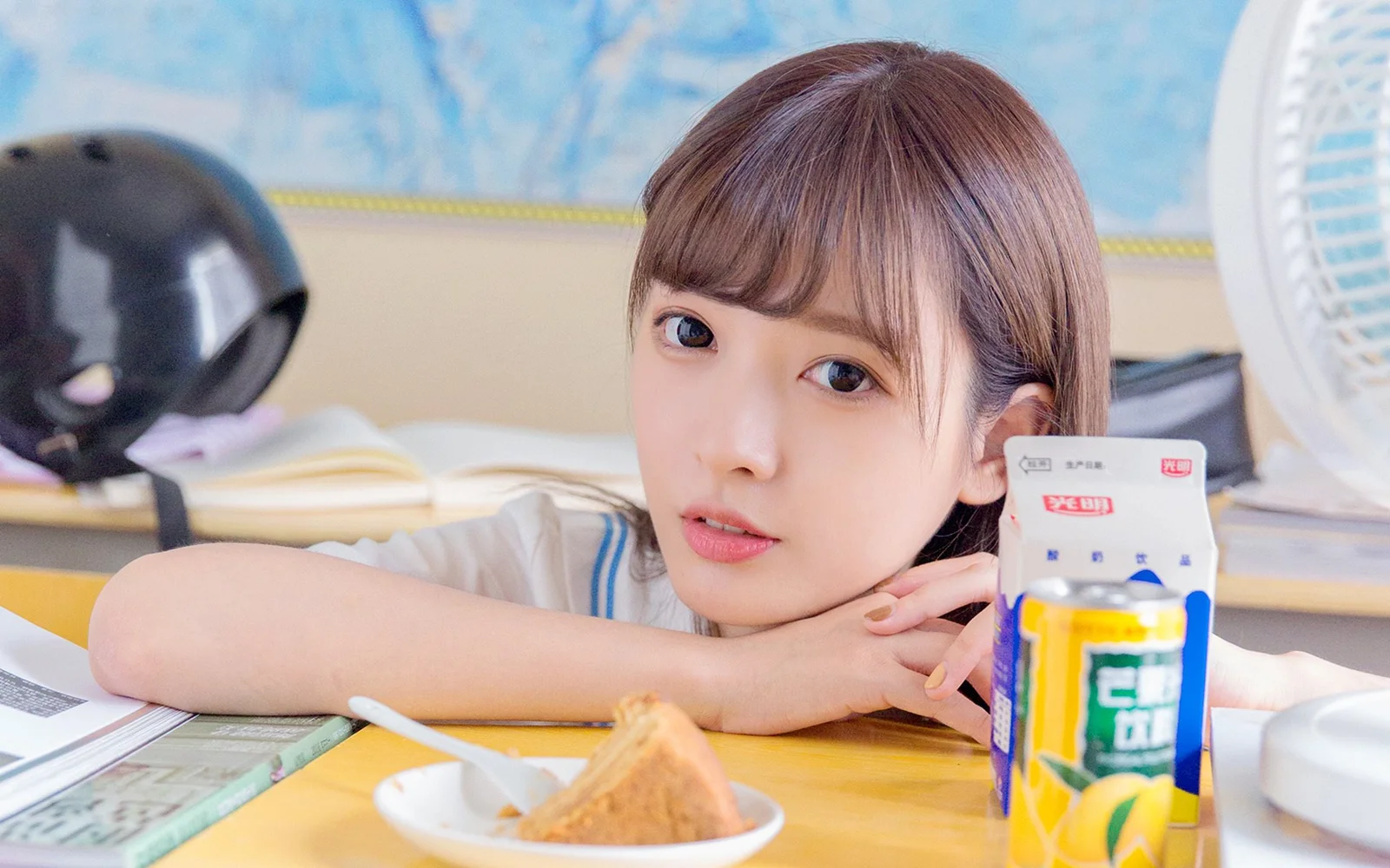 젊은 여성이 테이블에 팔을 올리고 밝은 실내에서 카메라를 바라보는 인물 사진입니다.