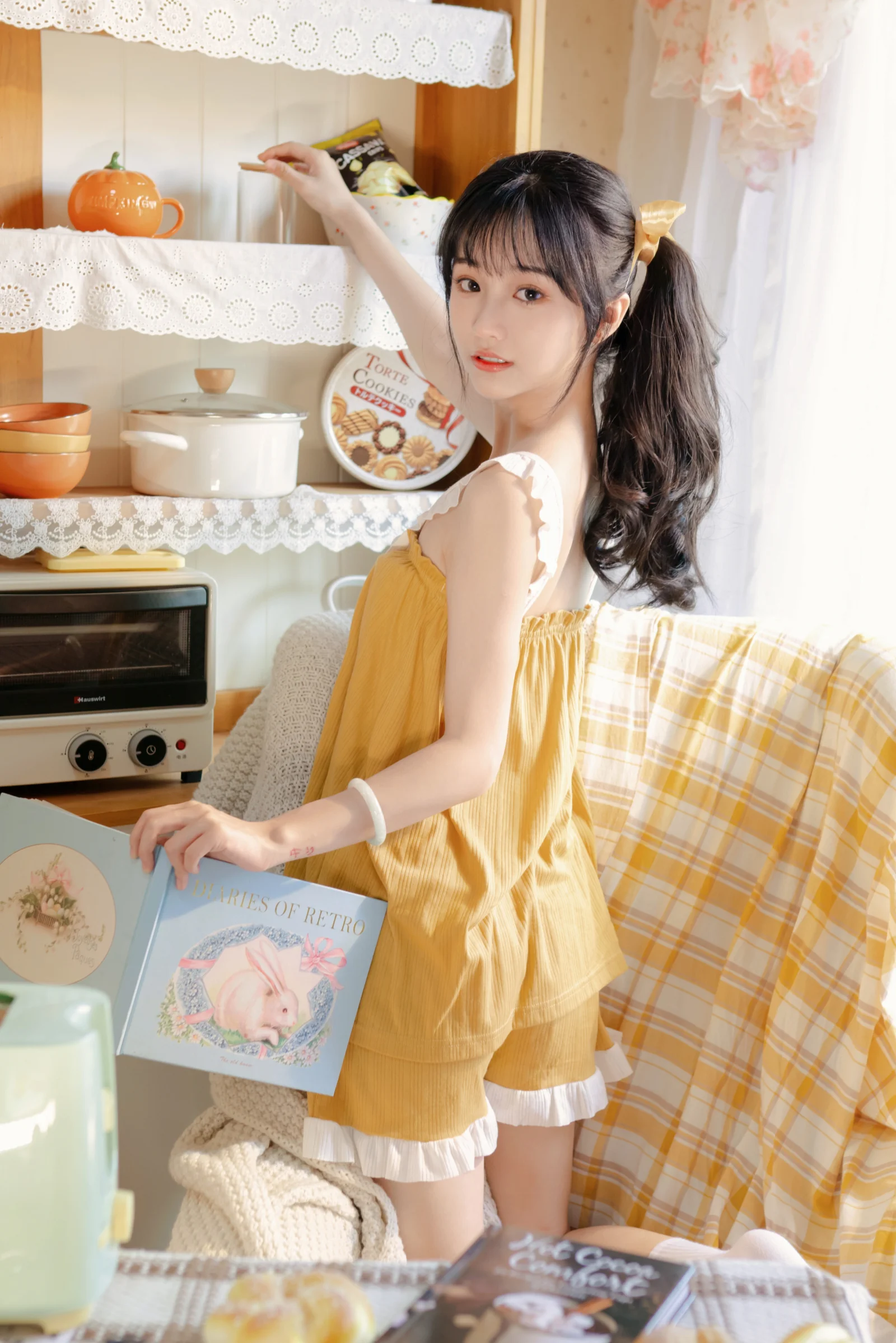 黄色いワンピースを着た女性が明るく居心地のよいキッチンに立っています。