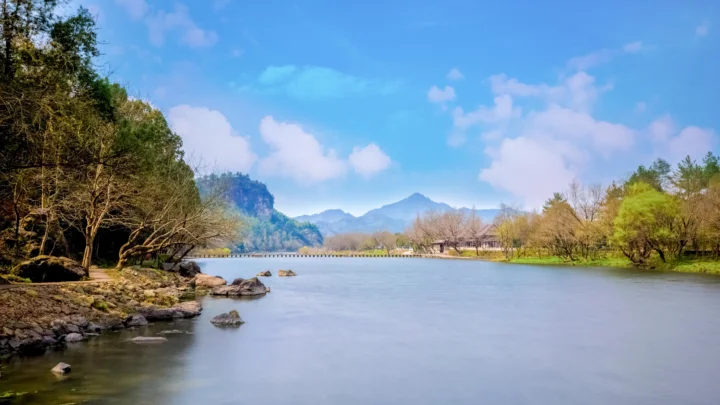 湖水、山峦与岸边树木在晴朗天空下构成宁静的自然风景。