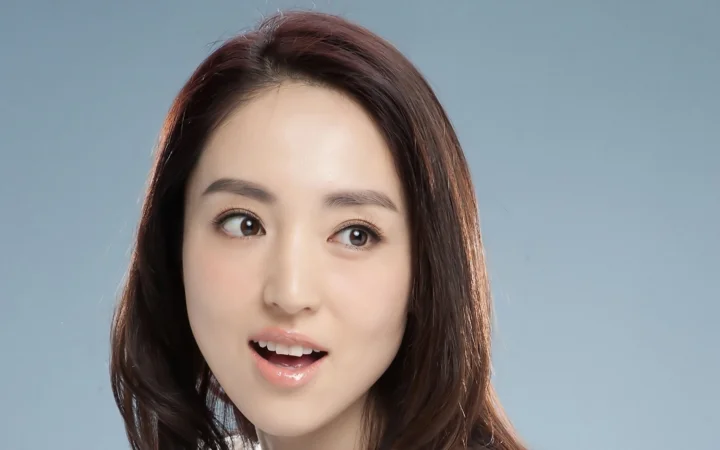 연한 청회색 배경 앞에서 자연스러운 표정을 짓고 있는 성인 여성의 클로즈업 초상입니다.