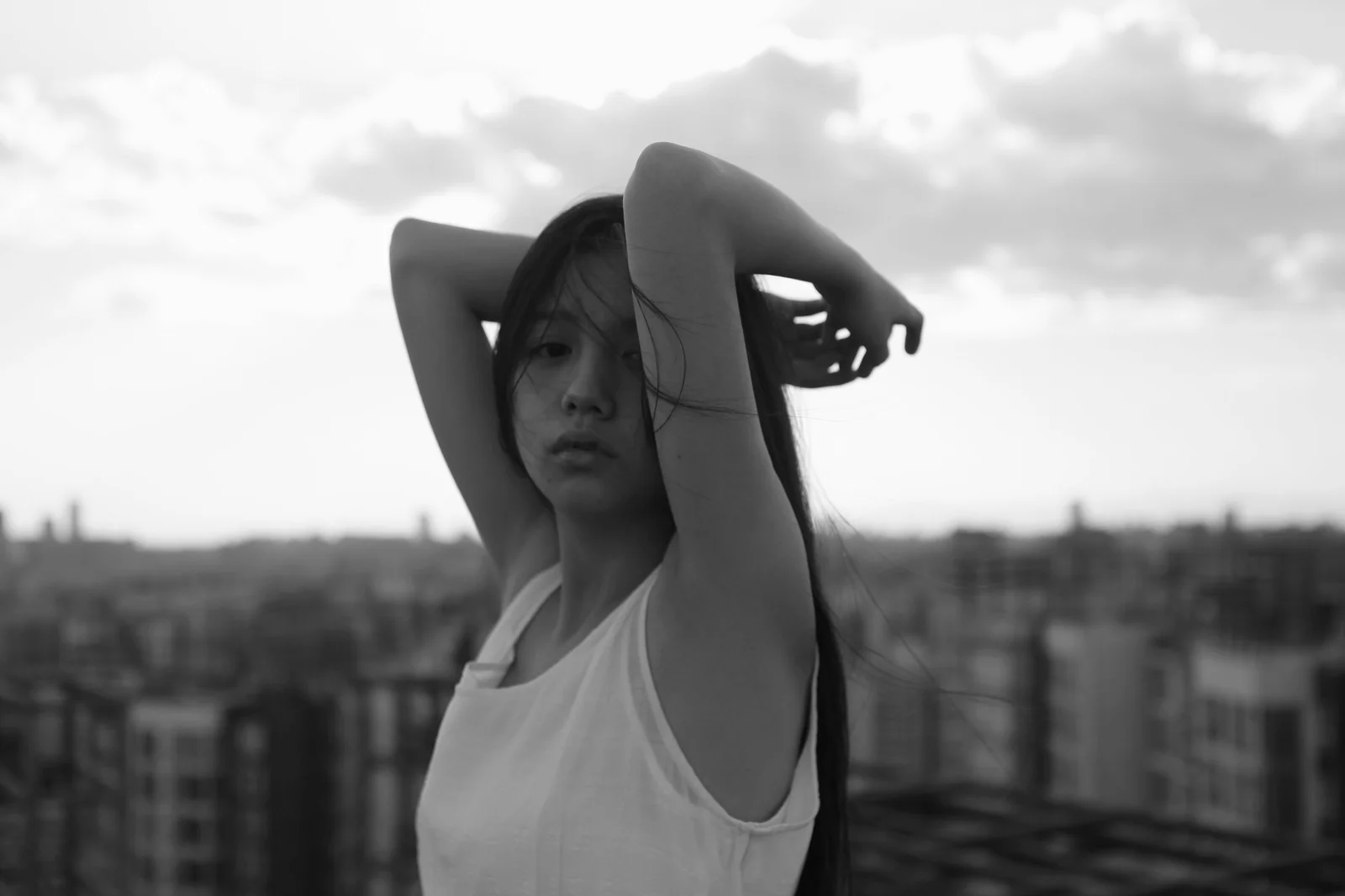 一名成年女性在城市天际线前举起双臂，画面以黑白色调呈现。