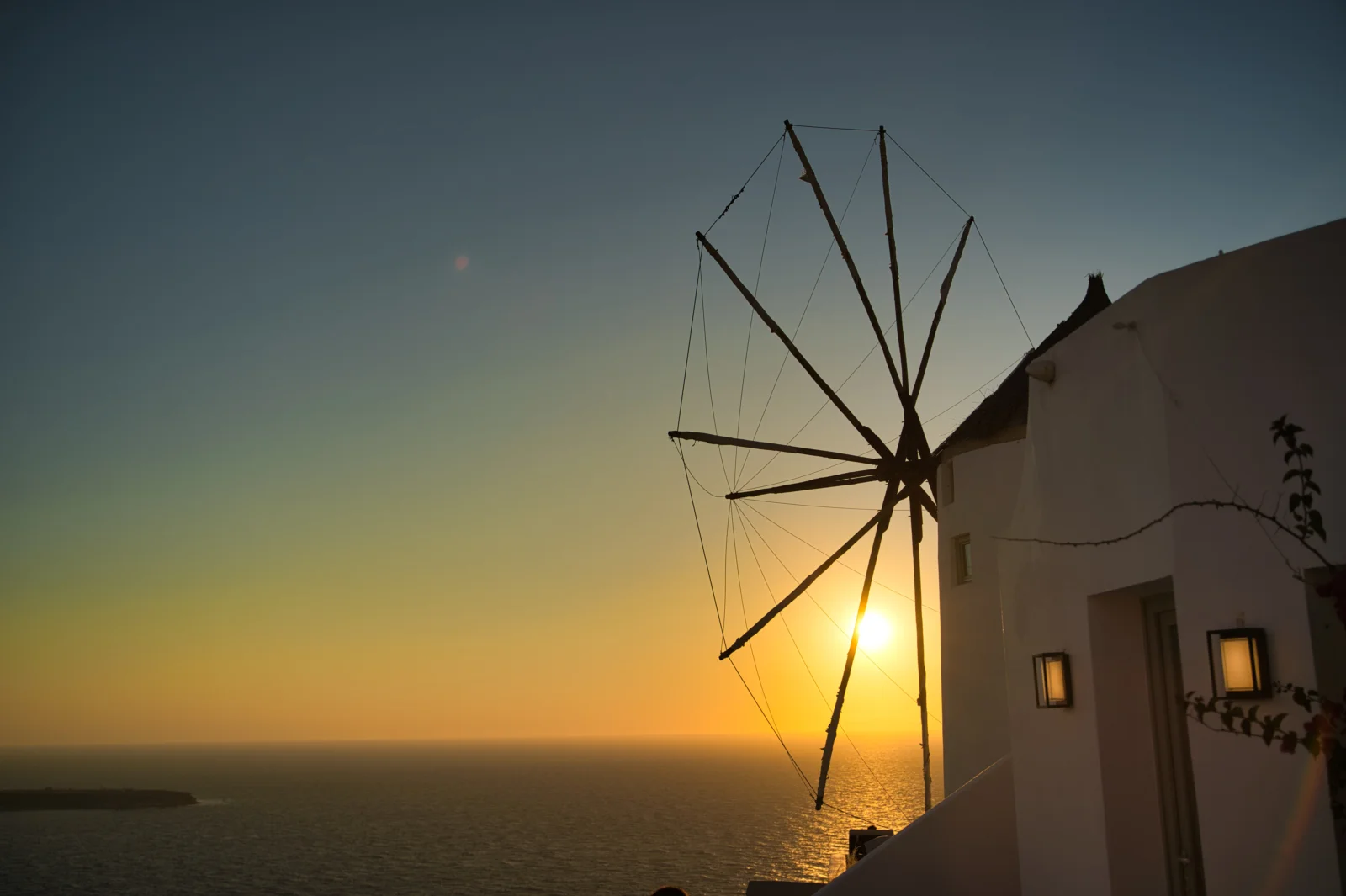 夕阳映照着海面，传统风车和白色建筑坐落在海岸边。
