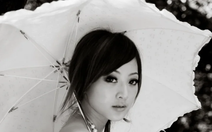 一名成年女性在白色雨伞前的黑白肖像画面。