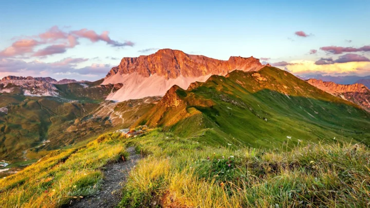 夕阳映照着壮丽的高山、绿色山脊和山间草甸。