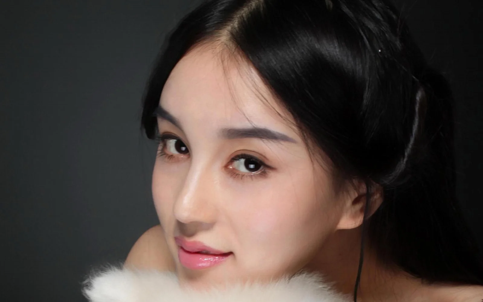 一位黑发女性在深色背景前的近距离肖像。