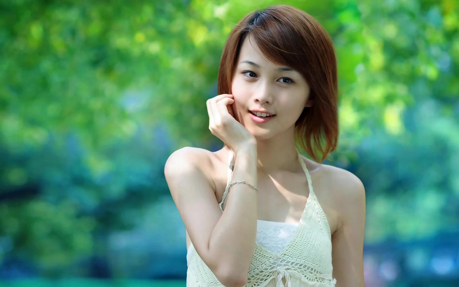 一名成年女性在绿色户外背景前微笑看向镜头。