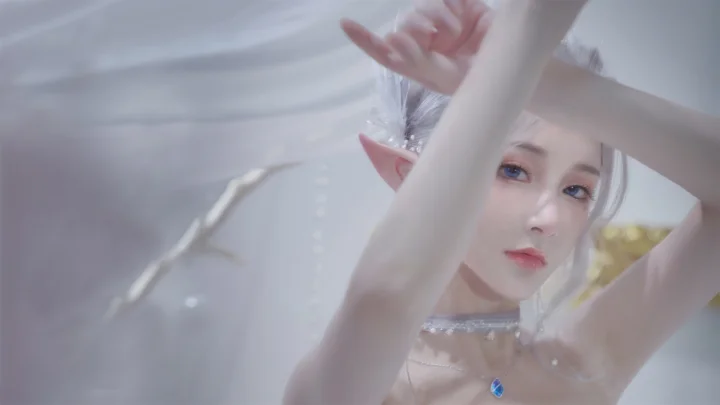 一位银发精灵造型的女性近距离面对镜头，柔和的浅色背景衬托出她的面容与尖耳朵。