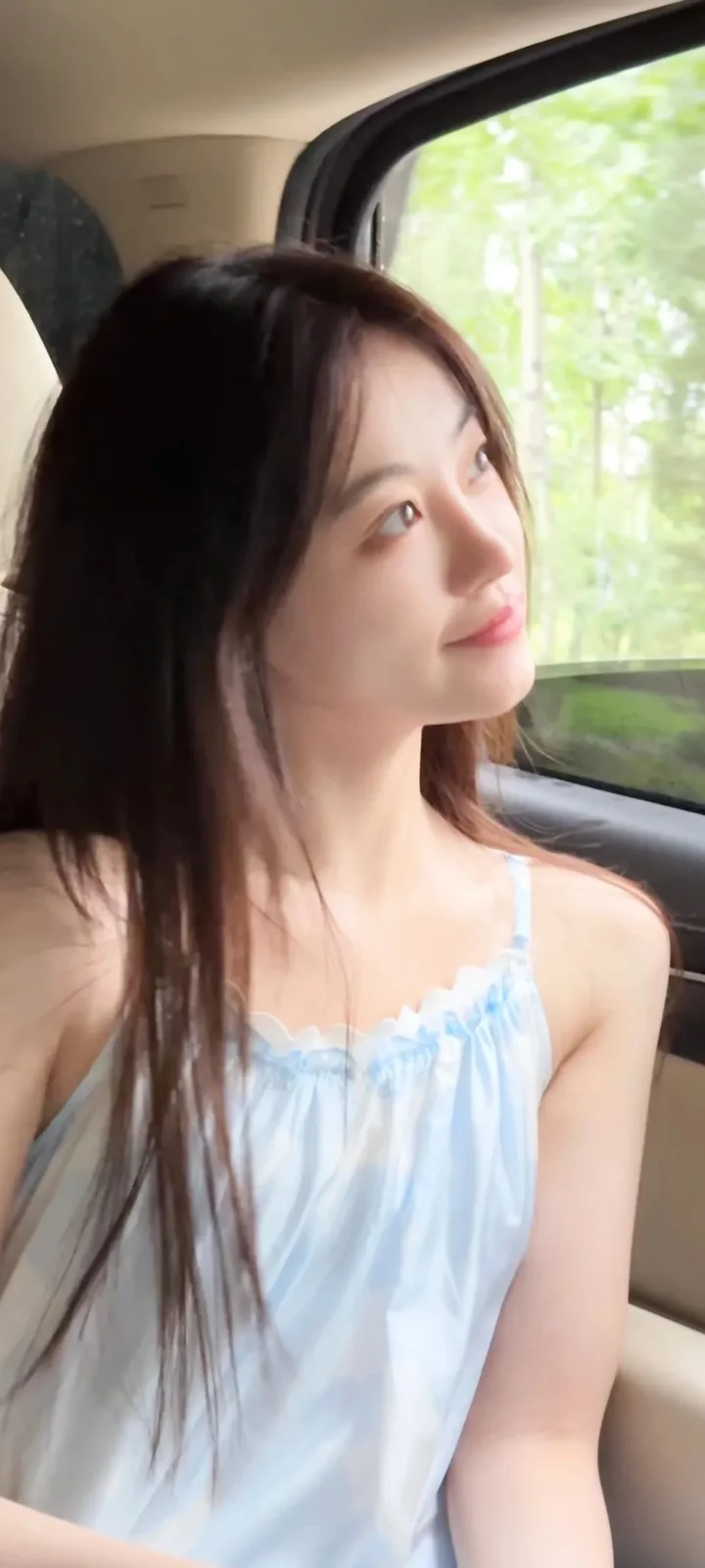 一位成年女性坐在车内靠近车窗的位置，穿着浅蓝色上衣。