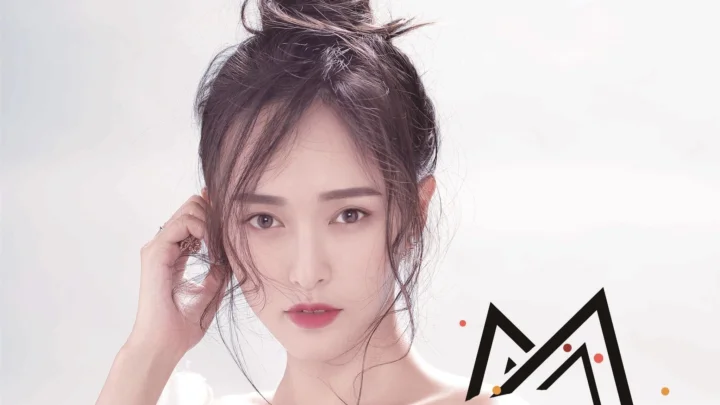 밝은 흰색 배경 앞에 머리를 올려 묶은 여성의 클로즈업 초상이다.