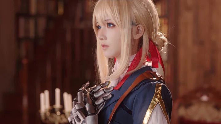 金髪の女性がコスプレ衣装で、温かみのある木造の室内を背景に横向きに立っている。