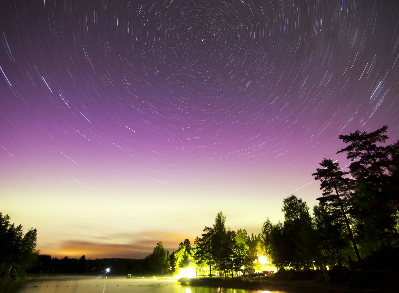 紫色夜空中环形星轨划过天际，下方可见树林与湖面倒影。