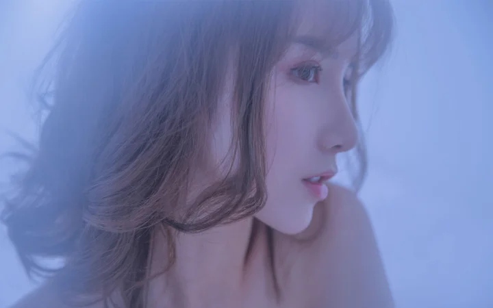 一名女性在柔和蓝光下呈现侧脸近景。