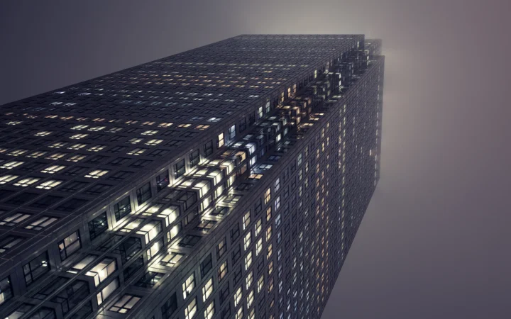 一座布满发光窗户的高层建筑从低角度延伸向夜空。