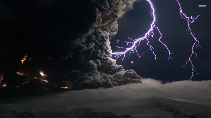 夜空中的闪电照亮了喷发的火山、浓重烟云和山地轮廓。