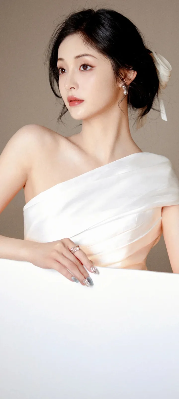 一名成年女性身穿白色单肩礼服，在浅色背景前呈现优雅肖像。