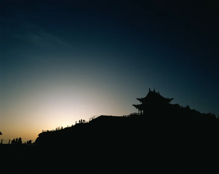 夕阳映照下，山脊上的古建筑呈现出深色剪影。
