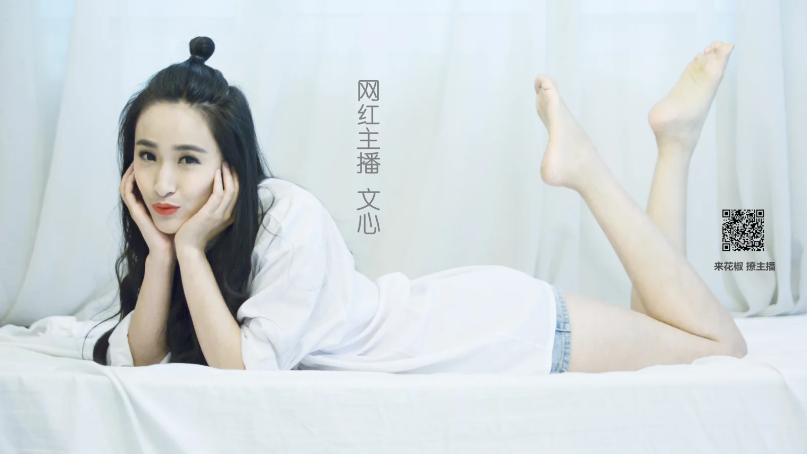 一名女子穿着白色上衣躺在床上，双手托腮并抬起双腿。