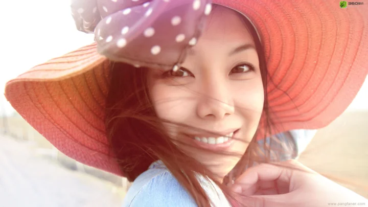 챙이 넓은 모자를 쓴 성인 여성이 밝은 야외 빛 속에서 미소 짓고 있다.