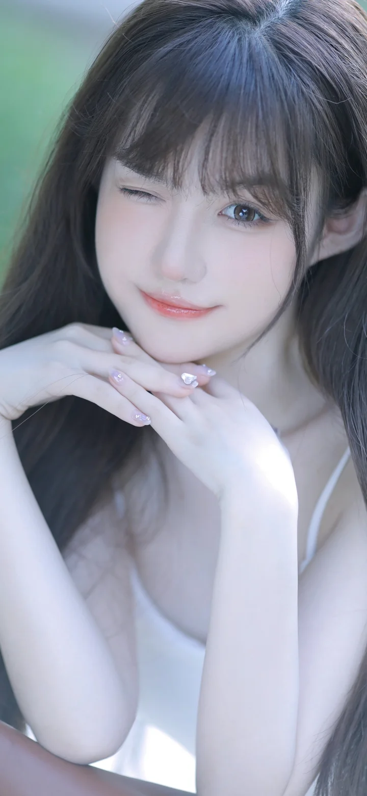 一名长发女性双手托着下巴，面向镜头摆出肖像姿势。