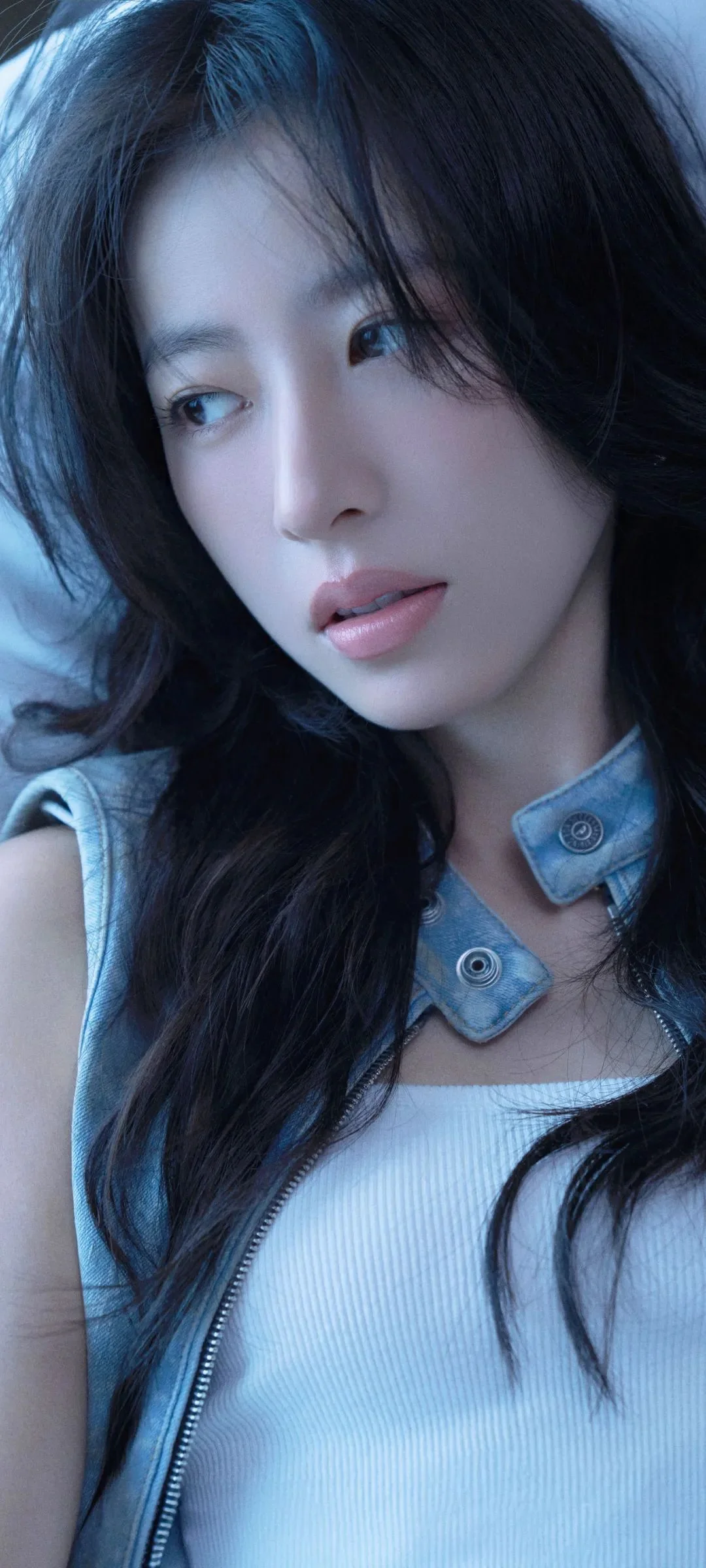 긴 머리의 여성이 연한 파란색 데님 재킷과 민소매 상의를 입은 차가운 푸른 톤의 클로즈업 인물 사진입니다.