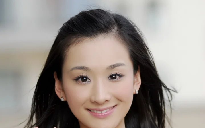 一名成年女性面向镜头微笑，黑色长发垂在肩侧。