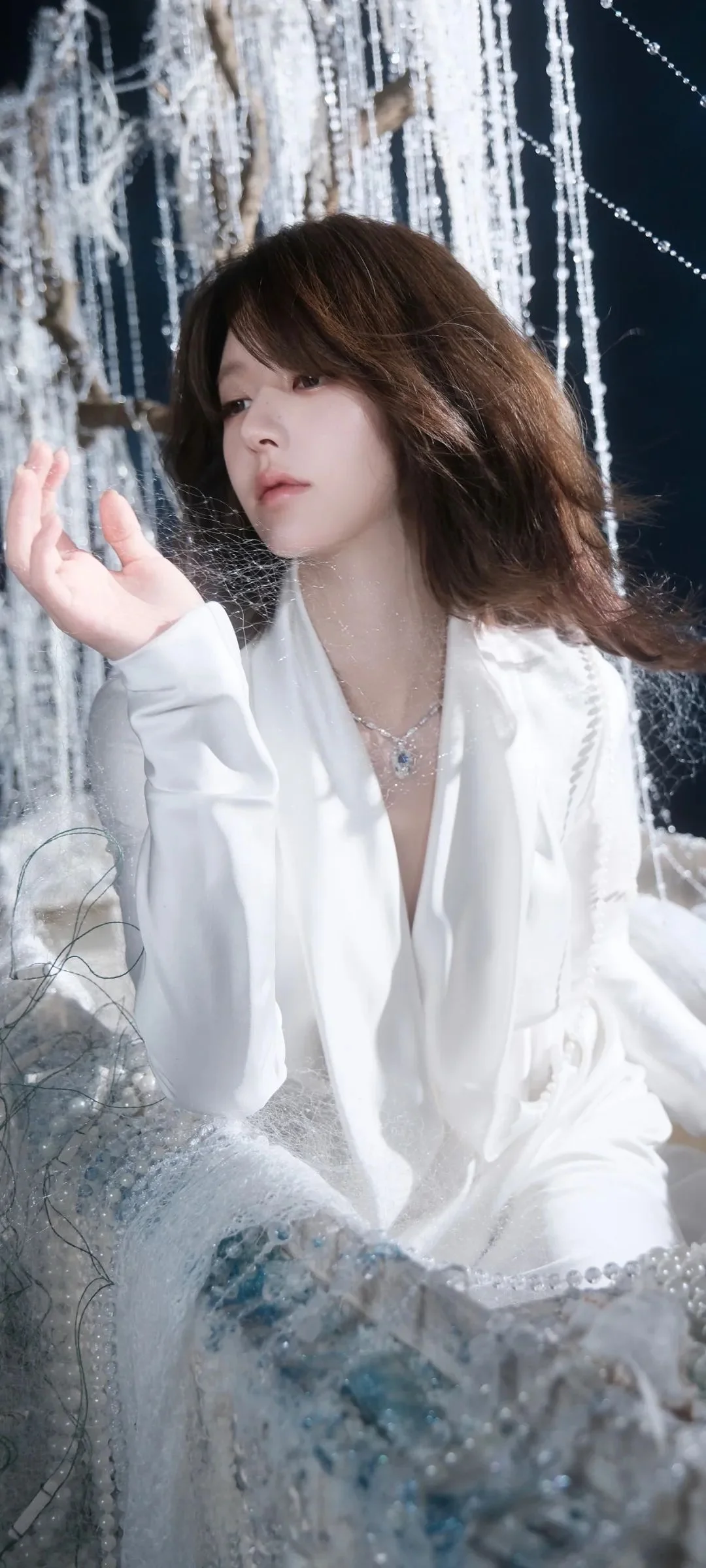 一位身穿白色服装的女性在闪亮的悬挂装饰前摆姿势。
