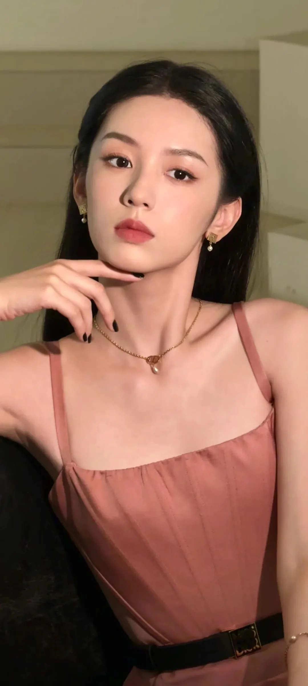 一位成年女性身穿粉色裙装，在室内面对镜头摆姿势。