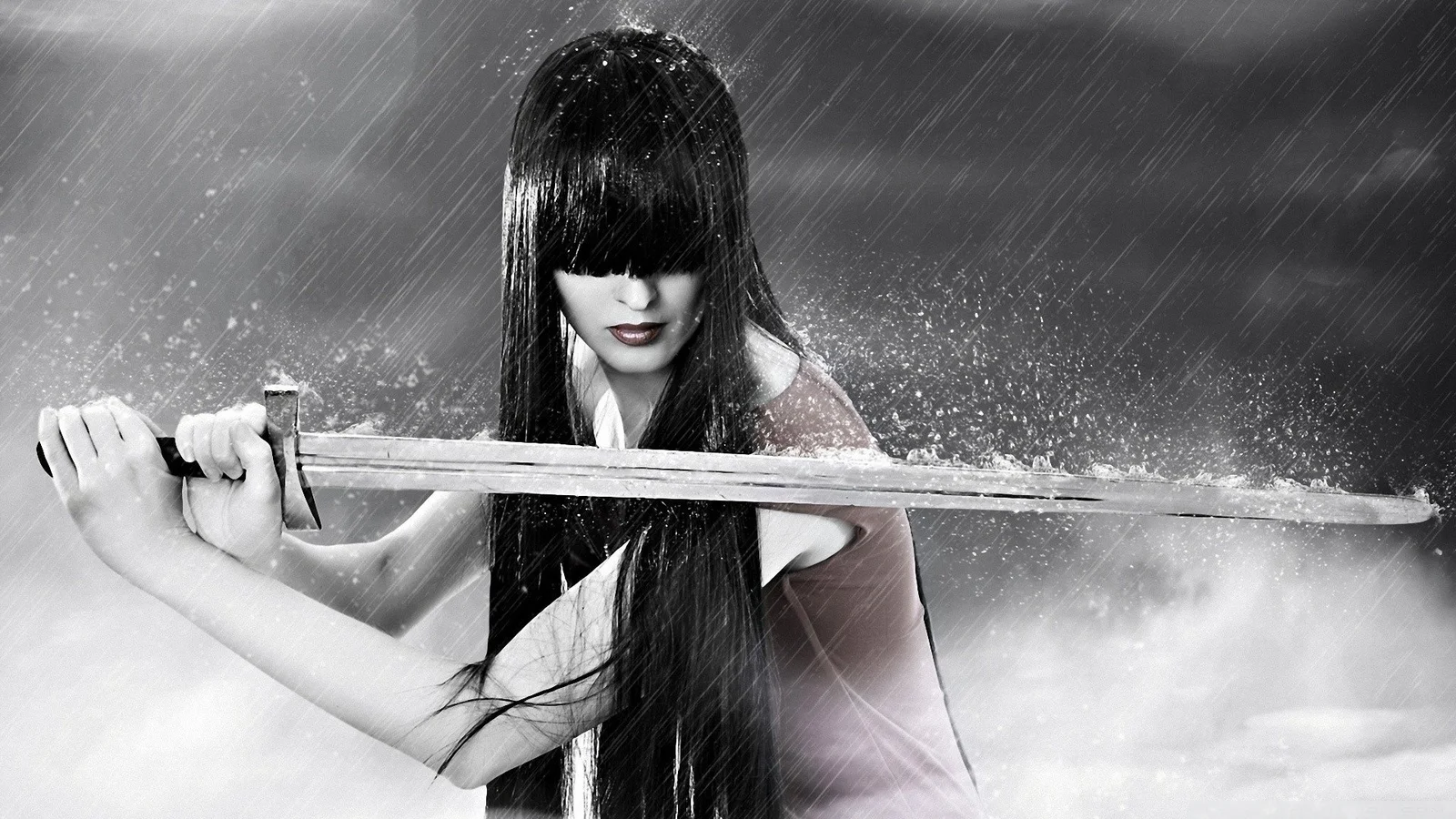 長い髪の女性が雨の中で剣を横に構えたモノクロの場面です。