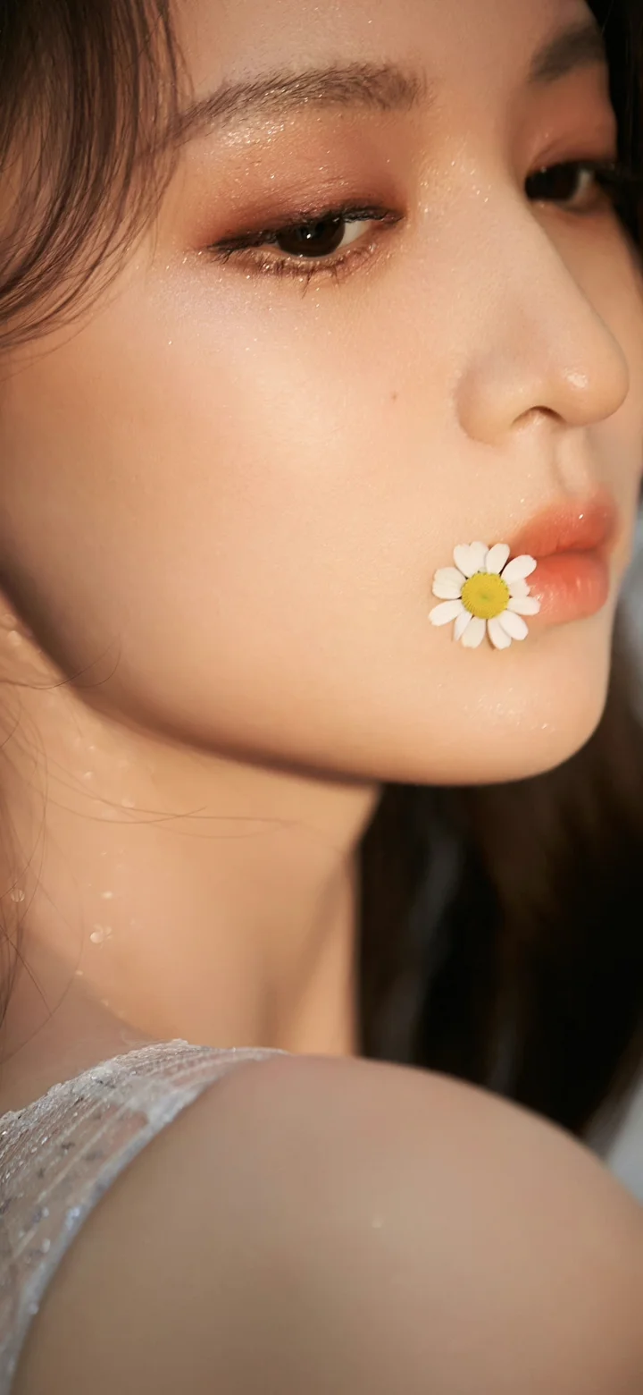 一位女性的侧脸特写，嘴角含着一朵小雏菊，肌肤和眼妆清晰可见。