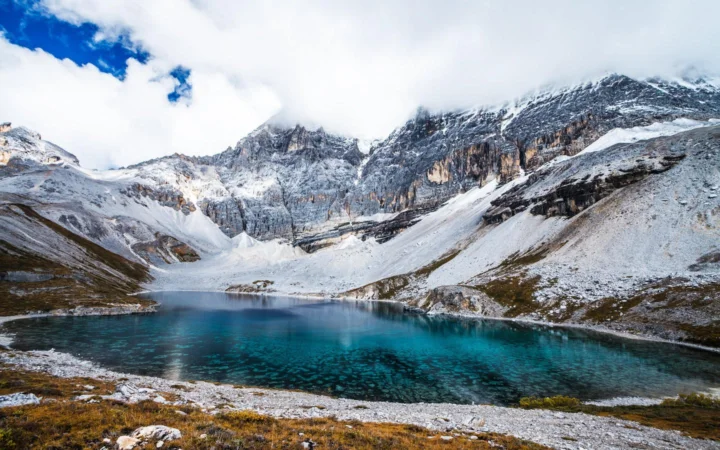 白雪覆盖的高山环绕着一片清澈的蓝绿色湖泊。