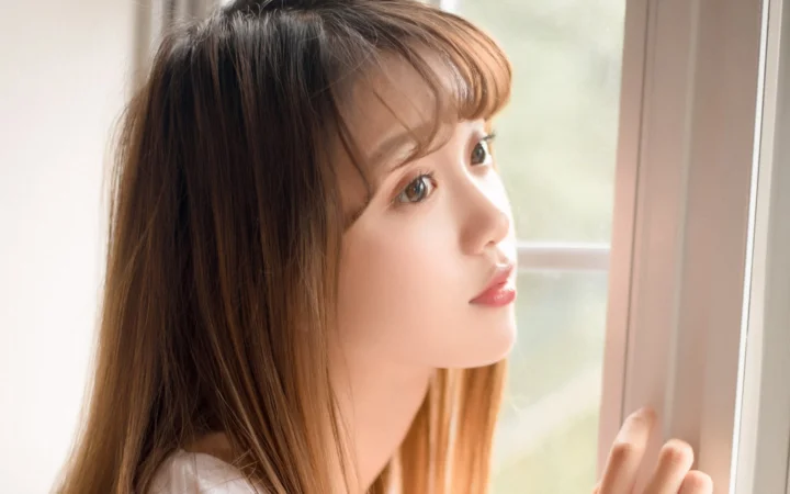 一名女性在窗边的侧脸近照，柔和光线映照着她的面容。