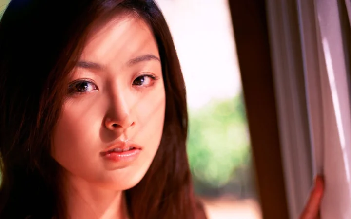 一名成年女性在窗边的近距离肖像，柔和光线映照在她的脸上。