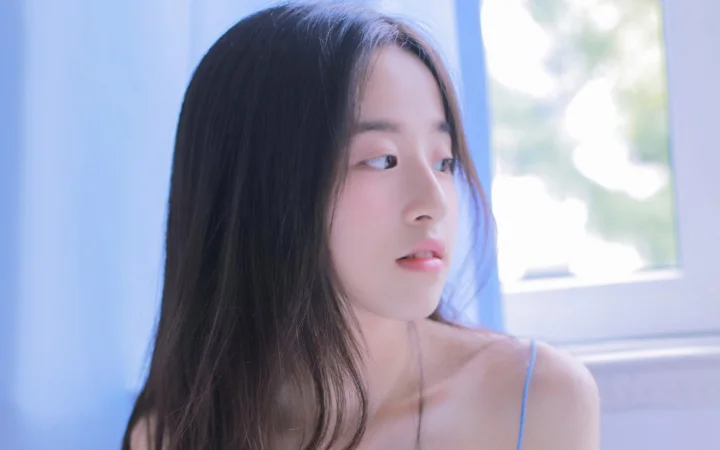 一位长发女性在窗边以侧脸望向窗外。