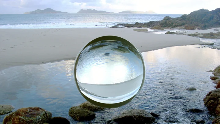 海滩浅水与礁石间放置着一颗映照海面景色的透明水晶球。