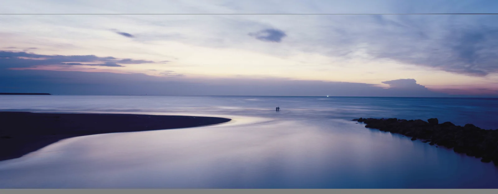 暮色天空下，宁静海湾与沙滩延伸至远方海面。