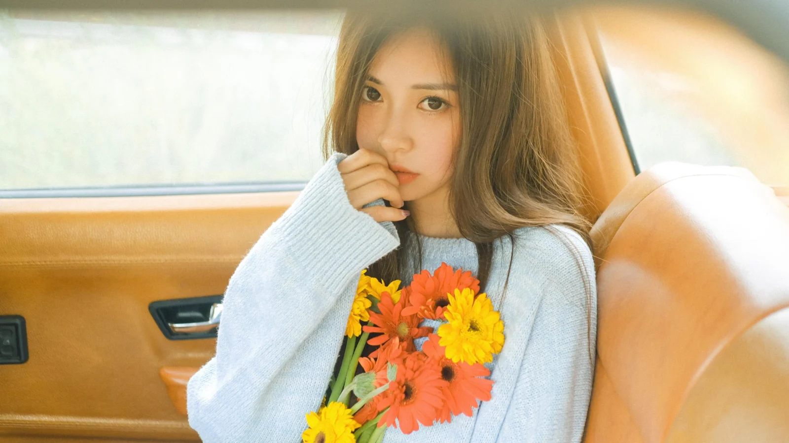 一名女性坐在汽车内，手捧一束鲜艳的花朵。