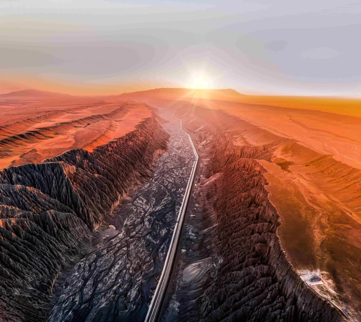 夕阳照耀下，一条公路穿过广阔的荒漠峡谷。