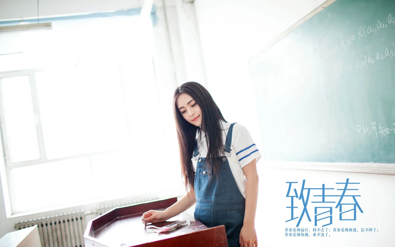 一名年轻女子站在明亮的教室里，身旁是黑板和讲台。