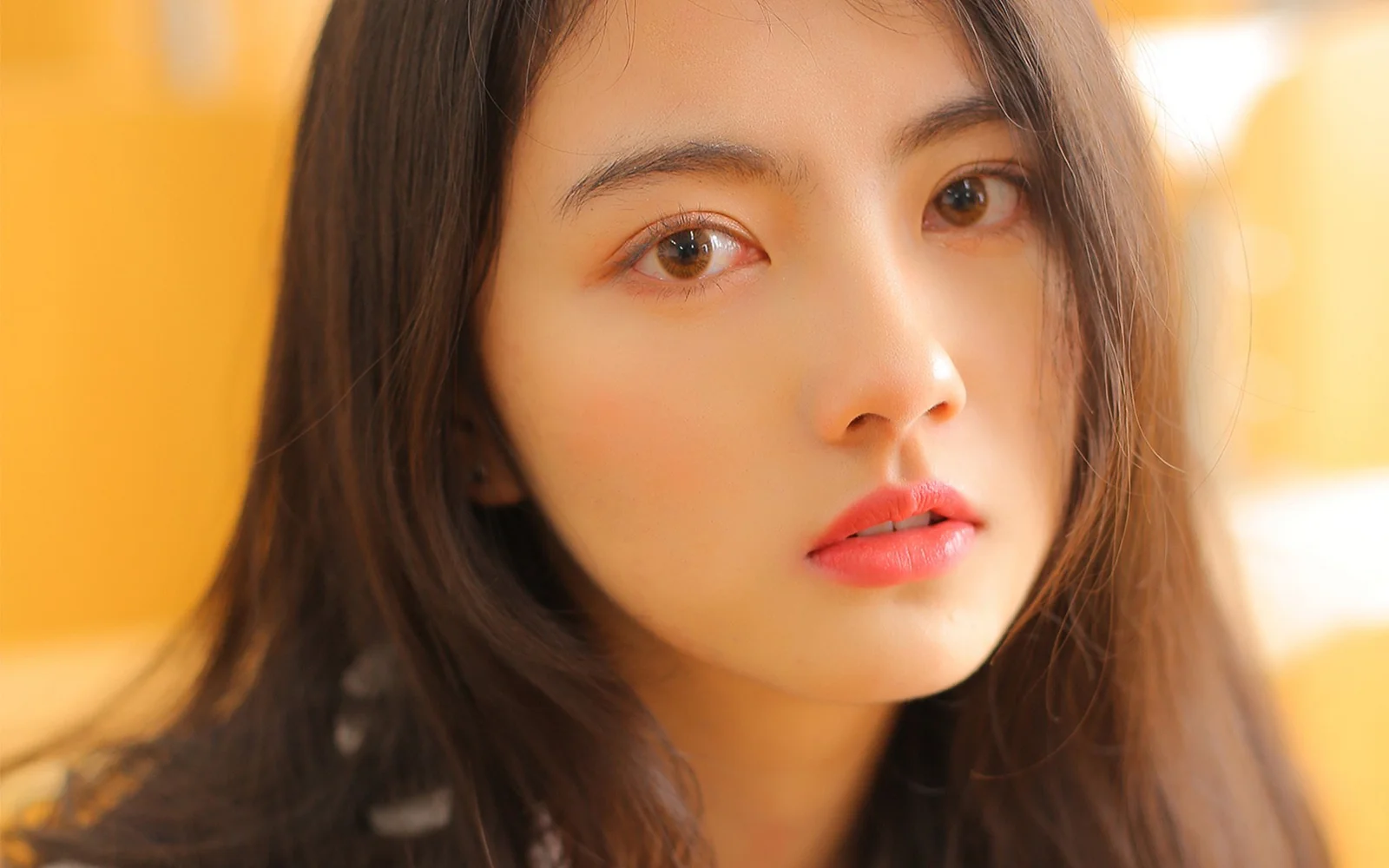 一位棕色长发女性的面部特写沐浴在温暖的金色光线中。