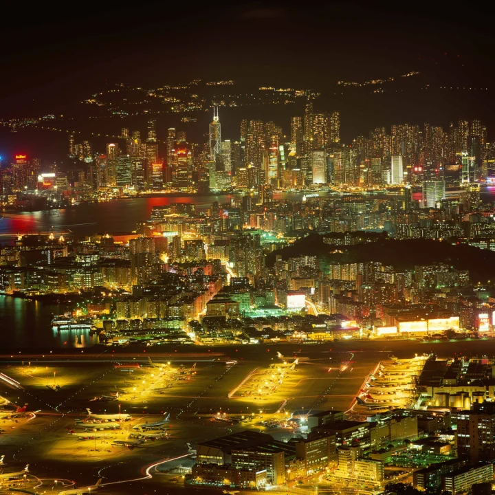 夜色中的城市天际线与灯火通明的机场俯瞰景象映照在水面上。