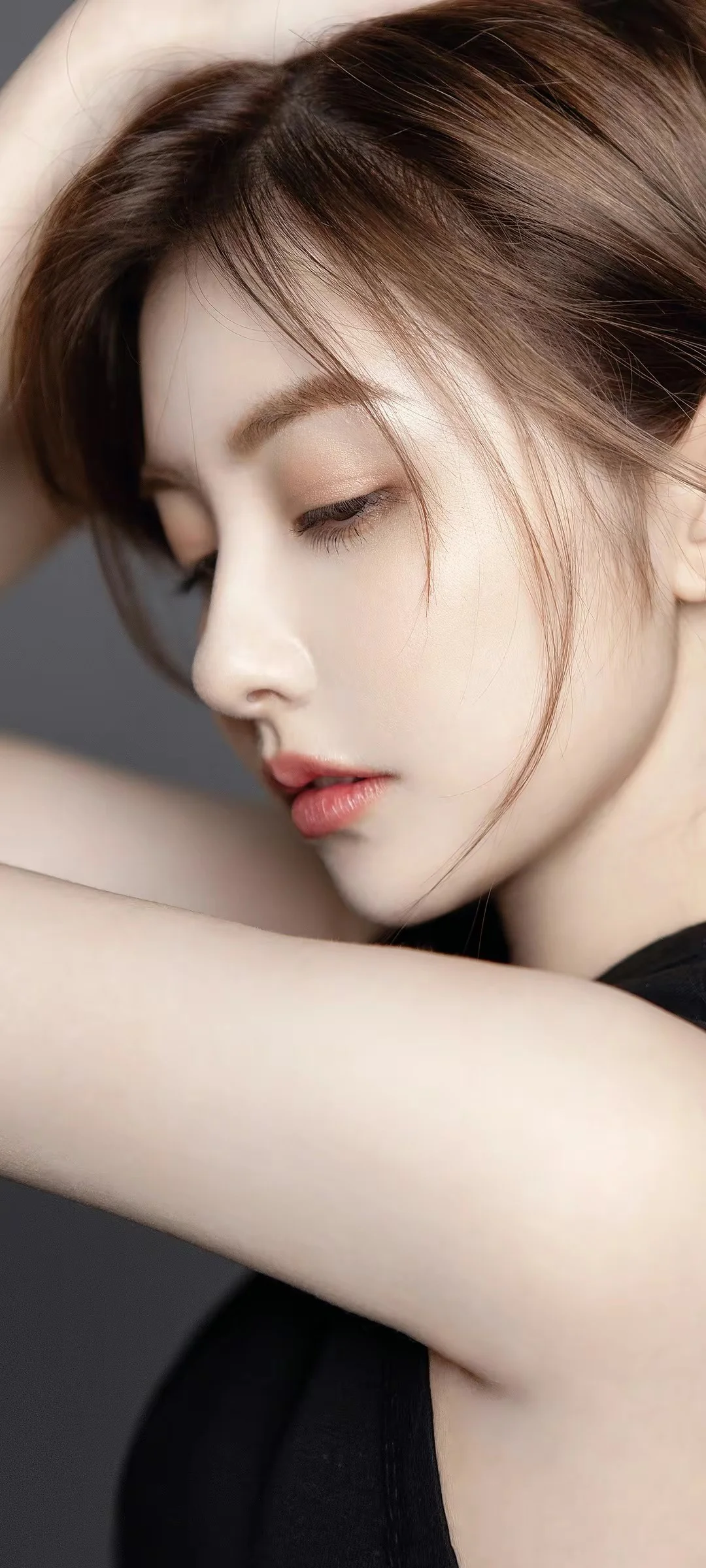 갈색 긴 머리의 여성이 눈을 감고 팔에 기대어 있는 부드러운 옆모습 클로즈업입니다.