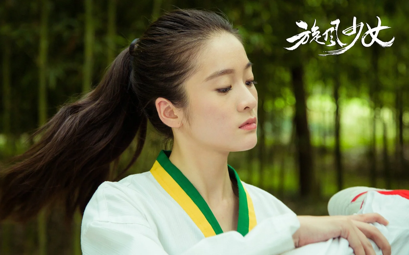 포니테일을 한 여성이 푸른 숲을 배경으로 옆모습을 보이고 있습니다.
