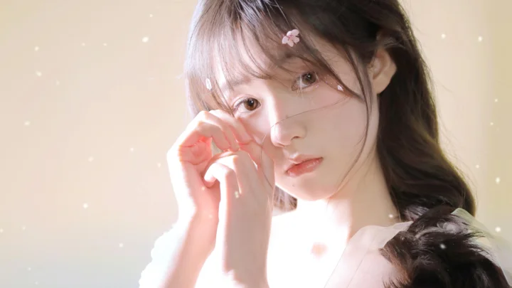 一位长发女性在柔和明亮的光线下直视镜头，脸侧点缀着小花发饰。