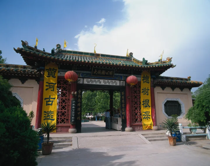 蓝天下，一座装饰华丽的中式古建筑门楼立于庭院入口。