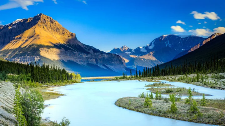 阳光照耀的群山、森林与浅蓝色河流构成壮丽的自然风景。